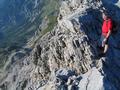Herbie blickt ehrfurchtsvoll am schmalen Gipfelgrat in die Tiefe, bevor er einen Gipfelsch. spendiert