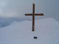 Im kalten Wind am Gipfelkreuz. Die Gipfelbuchkassette ragt kaum aus dem Schnee heraus.