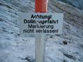 Einige Tafeln warnen vor dem Verlassen des markierten Weges im dolinenreichen Karstgelnde.