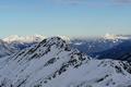 Im Norden der benachbarte Pleschnitzzinken, auf dem man das Gipfelkreuz erkennen kann. Im Hintergrund die sonnenbeschienenen Gipfel des Toten Gebirges (links) sowie der Haller Mauern in den Ennstaler Alpen (rechts).