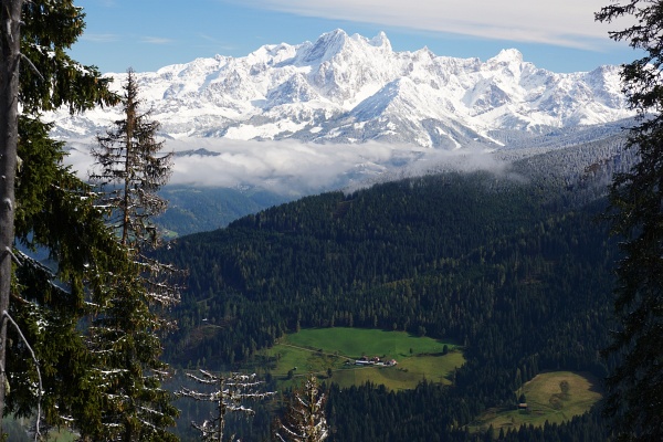 Winterliche Berggipfel (Dachstein) über grünen Tälern.
